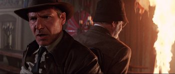 Movie still from “Indiana Jones and the Last Crusade” (1989), directed by Steven Spielberg – A man in a hat and a jacket is sitting next to another man in a hat and a jacket; Close Up shot, Low angle
