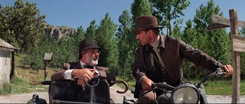 Movie still from “Indiana Jones and the Last Crusade” (1989), directed by Steven Spielberg – Two men sitting on top of a bicycle; Wide shot, Over the shoulder angle