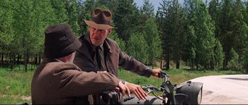 Movie still from “Indiana Jones and the Last Crusade” (1989), directed by Steven Spielberg – An older man wearing a hat is on a motorcycle; Medium shot, Over the shoulder angle