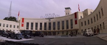 Movie still from “Indiana Jones and the Last Crusade” (1989), directed by Steven Spielberg – A building that has a large sign on top of it that says berlin flughafen; Extreme Wide shot, Low angle