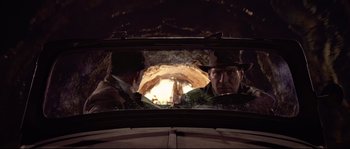 Movie still from “Indiana Jones and the Last Crusade” (1989), directed by Steven Spielberg – Two men in a car looking out the window at a cave; Close Up shot, Over the shoulder angle