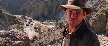 Movie still from “Indiana Jones and the Last Crusade” (1989), directed by Steven Spielberg – A person wearing a hat near some rocks; Close Up shot, Low angle