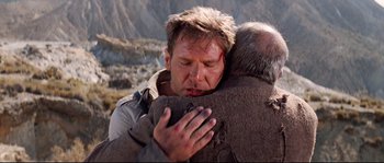 Movie still from “Indiana Jones and the Last Crusade” (1989), directed by Steven Spielberg – A man hugging another man in a field; Close Up shot, Low angle