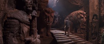 Movie still from “Indiana Jones and the Last Crusade” (1989), directed by Steven Spielberg – A man walking down the stairs in a cave; Wide shot, Low angle