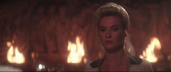 Movie still from “Indiana Jones and the Last Crusade” (1989), directed by Steven Spielberg – A beautiful blonde woman with a fire in the background; Close Up shot, Over the shoulder angle