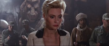 Movie still from “Indiana Jones and the Last Crusade” (1989), directed by Steven Spielberg – A woman in a white and black jacket looking at the camera; Close Up shot, Over the shoulder angle
