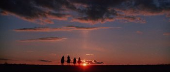 Movie still from “Indiana Jones and the Last Crusade” (1989), directed by Steven Spielberg – A group of people riding horses in the sunset; Extreme Wide shot, Low angle