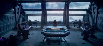 Movie still from “Lost in Space” (2018), created by Irwin Allen – A person standing in front of a table in a room; Extreme Wide shot, High angle