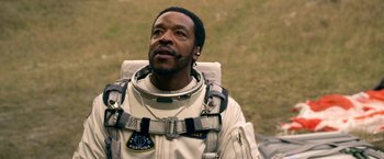 Movie still from “Lost in Space” (2018), created by Irwin Allen – A man in a spacesuit looking up at the sky; Close Up shot, Over the shoulder angle