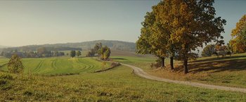 Movie still from “Inglourious Basterds” (2009), directed by Quentin Tarantino – A dirt road running through a green field; Extreme Wide shot, High angle