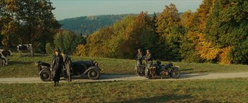 Movie still from “Inglourious Basterds” (2009), directed by Quentin Tarantino – A couple of men riding on the back of an old car; Extreme Wide shot, High angle