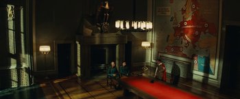 Movie still from “Inglourious Basterds” (2009), directed by Quentin Tarantino – Two men sitting on a chair in front of a fire place; Extreme Wide shot, High angle