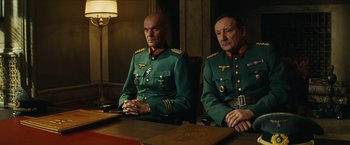 Movie still from “Inglourious Basterds” (2009), directed by Quentin Tarantino – A couple of men sitting at a wooden table; Medium shot, Low angle