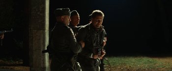 Movie still from “Inglourious Basterds” (2009), directed by Quentin Tarantino – A group of men standing next to each other on top of a field; Medium shot, Over the shoulder angle