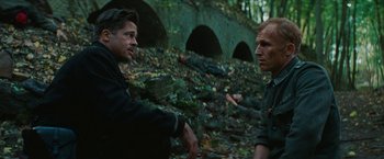 Movie still from “Inglourious Basterds” (2009), directed by Quentin Tarantino – Two men standing next to each other near a forest; Medium shot, Over the shoulder angle