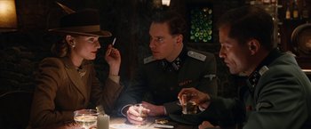 Movie still from “Inglourious Basterds” (2009), directed by Quentin Tarantino – A group of people sitting at a table with drinks; Medium shot, Over the shoulder angle