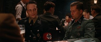 Movie still from “Inglourious Basterds” (2009), directed by Quentin Tarantino – A group of men sitting around a table; Medium shot, Over the shoulder angle