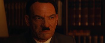 Movie still from “Inglourious Basterds” (2009), directed by Quentin Tarantino – A man in a suit and tie with a mustache; Close Up shot, High angle