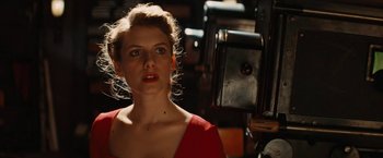 Movie still from “Inglourious Basterds” (2009), directed by Quentin Tarantino – A woman in a red dress is standing in front of a camera; Close Up shot, Low angle