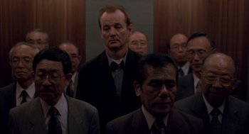 Movie still from “Lost in Translation” (2003), directed by Sofia Coppola – A group of men in suits and ties standing in a room; Medium shot, Low angle