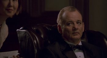 Movie still from “Lost in Translation” (2003), directed by Sofia Coppola – A man in a tuxedo sitting in a leather chair; Close Up shot, Low angle