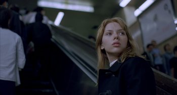 Movie still from “Lost in Translation” (2003), directed by Sofia Coppola – A woman in a black coat is standing in a train; Close Up shot, Low angle