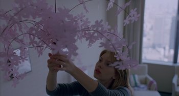 Movie still from “Lost in Translation” (2003), directed by Sofia Coppola – A woman holding a cell phone in front of a tree branch; Medium shot, Low angle