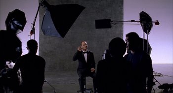 Movie still from “Lost in Translation” (2003), directed by Sofia Coppola – A man in a suit and bow tie is being filmed; Medium shot, Over the shoulder angle