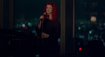 Movie still from “Lost in Translation” (2003), directed by Sofia Coppola – A woman with red curly hair is holding a microphone; Medium shot, Low angle