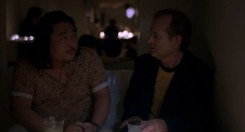 Movie still from “Lost in Translation” (2003), directed by Sofia Coppola – Two people sitting at a table talking to each other; Medium shot, Low angle