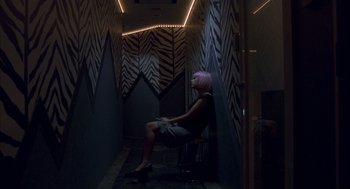 Movie still from “Lost in Translation” (2003), directed by Sofia Coppola – A woman sitting on a chair in a room with zebra print walls; Wide shot, High angle