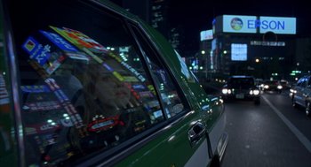 Movie still from “Lost in Translation” (2003), directed by Sofia Coppola – A woman sitting in the driver's seat of a green car; Close Up shot, Over the shoulder angle