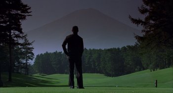 Movie still from “Lost in Translation” (2003), directed by Sofia Coppola – A man standing on top of a golf course holding a golf club; Wide shot, Low angle