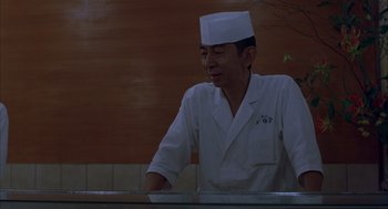 Movie still from “Lost in Translation” (2003), directed by Sofia Coppola – A man wearing a white hat standing in front of a counter; Medium shot, Low angle