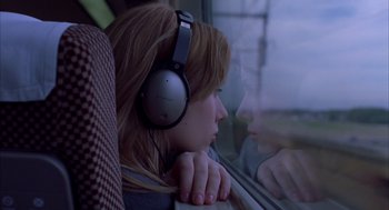 Movie still from “Lost in Translation” (2003), directed by Sofia Coppola – A woman wearing headphones looking out of a window; Close Up shot, High angle