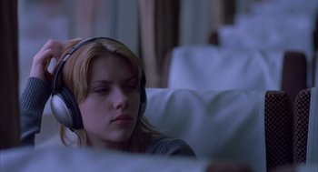 Movie still from “Lost in Translation” (2003), directed by Sofia Coppola – A woman wearing headphones sitting on top of a couch; Close Up shot, Over the shoulder angle