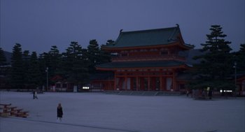 Movie still from “Lost in Translation” (2003), directed by Sofia Coppola – A person standing in front of a building at night time; Extreme Wide shot, High angle