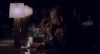 Movie still from “Lost in Translation” (2003), directed by Sofia Coppola – A man sitting at a table with a glass of whiskey; Medium shot, Low angle
