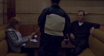 Movie still from “Lost in Translation” (2003), directed by Sofia Coppola – A group of people sitting around a table; Medium shot, Over the shoulder angle