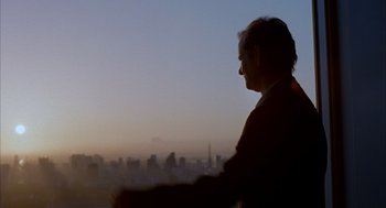 Movie still from “Lost in Translation” (2003), directed by Sofia Coppola – A man is looking out over a city skyline at dusk; Close Up shot, Low angle