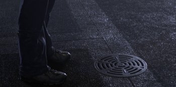 Movie still from “Love, Death & Robots” (2019), created by Tim Miller – A man standing next to a manhole cover on the ground; Extreme Close Up shot, Overhead angle