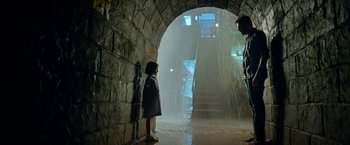 Two children are standing in a tunnel in the rain