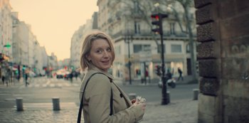 Movie still from “Lupin” (2021), created by Tigran Rosine – A woman is walking down the street holding a cup; Close Up shot, Over the shoulder angle