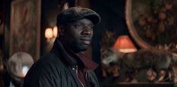 Movie still from “Lupin” (2021), created by Tigran Rosine – A man wearing a hat and a jacket; Close Up shot, Over the shoulder angle