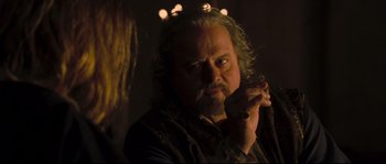 Movie still from “Kingdom of Heaven” (2005), directed by Ridley Scott – A person with a beard smoking a cigarette; Close Up shot, Over the shoulder angle