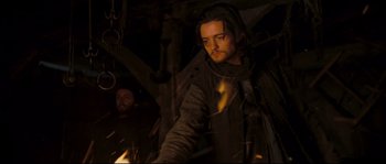 Movie still from “Kingdom of Heaven” (2005), directed by Ridley Scott – A man standing next to another man in a dark room; Medium shot, Low angle