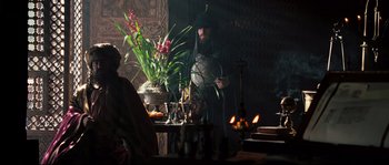 Movie still from “Kingdom of Heaven” (2005), directed by Ridley Scott – A man standing in front of a table with a plant; Wide shot, Over the shoulder angle