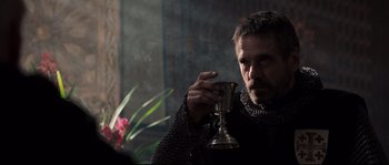 Movie still from “Kingdom of Heaven” (2005), directed by Ridley Scott – A man in chain mail holding a wine goblet; Close Up shot, Over the shoulder angle