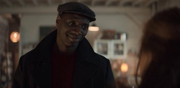 Movie still from “Lupin” (2021), created by Tigran Rosine – A man wearing a hat and a jacket; Close Up shot, Over the shoulder angle