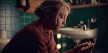 Movie still from “Lupin” (2021), created by Tigran Rosine – A woman sitting in front of a sink looking down; Close Up shot, High angle